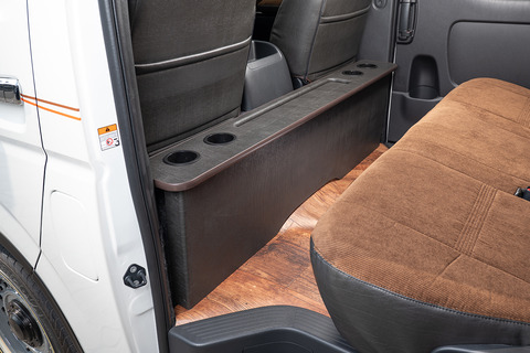 200系ハイエースの後部座席にヴィンテージブラックレザーのテーブルが設置してあるのが助手席側から見える。