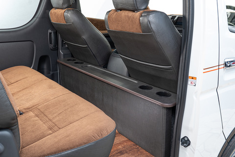 200系ハイエースの後部座席にヴィンテージブラックレザーのテーブルが設置してあり、前列シートを後ろにリクライニングしている。