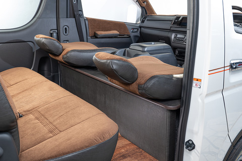 200系ハイエースの後部座席にヴィンテージブラックレザーのテーブルが設置してあり、前列シートを後ろに最大までリクライニングしている。