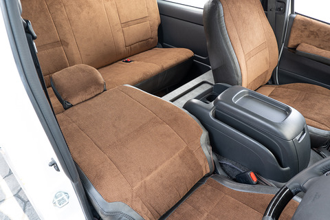 200系ハイエースの後部座席にヴィンテージブラックレザーのテーブルが設置してあり、運転席シートを後ろに最大までリクライニングしているのを運転席側から見える。